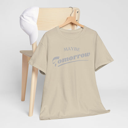 Chic Maybe Tomorrow T-Shirt hanging alongside a white cap on a stylish chair, exemplifying relaxed luxury and casual sophistication.