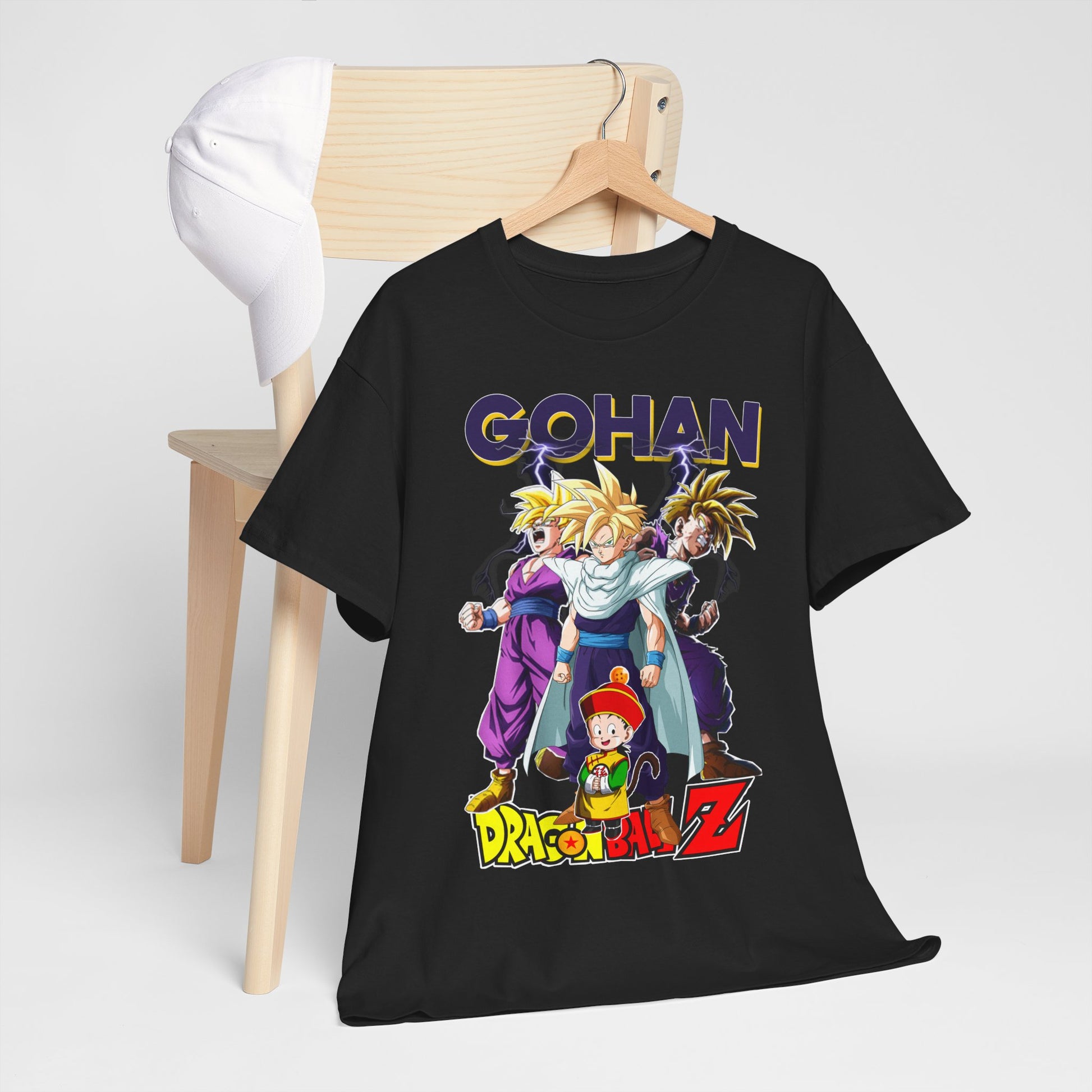 Stylish Gohan Ascends T-Shirt on a wooden chair paired with a white cap, displaying iconic characters from Dragon Ball Z in vivid colour.