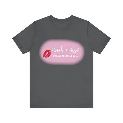 Sabrina Carpenter Inspired Unisex Short Sleeve Tee with Vibrant Lipstick Print in charcoal grey, elegantly displaying 'Short n sweet, I'm working Late...' complemented by a chic lipstick design.