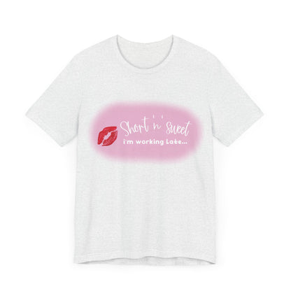 Front view of the Sabrina Carpenter Inspired Unisex Short Sleeve Tee featuring a vibrant lipstick print with the text 'Short 'n' sweet, I'm working late...' on a light pastel background.