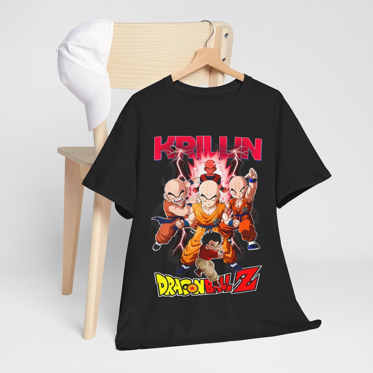 Luxurious black Dragon Ball Z T-shirt featuring Krillin and iconic characters amidst electrifying energy graphics, displayed with a fashionable cap on a minimalist wooden chair.
