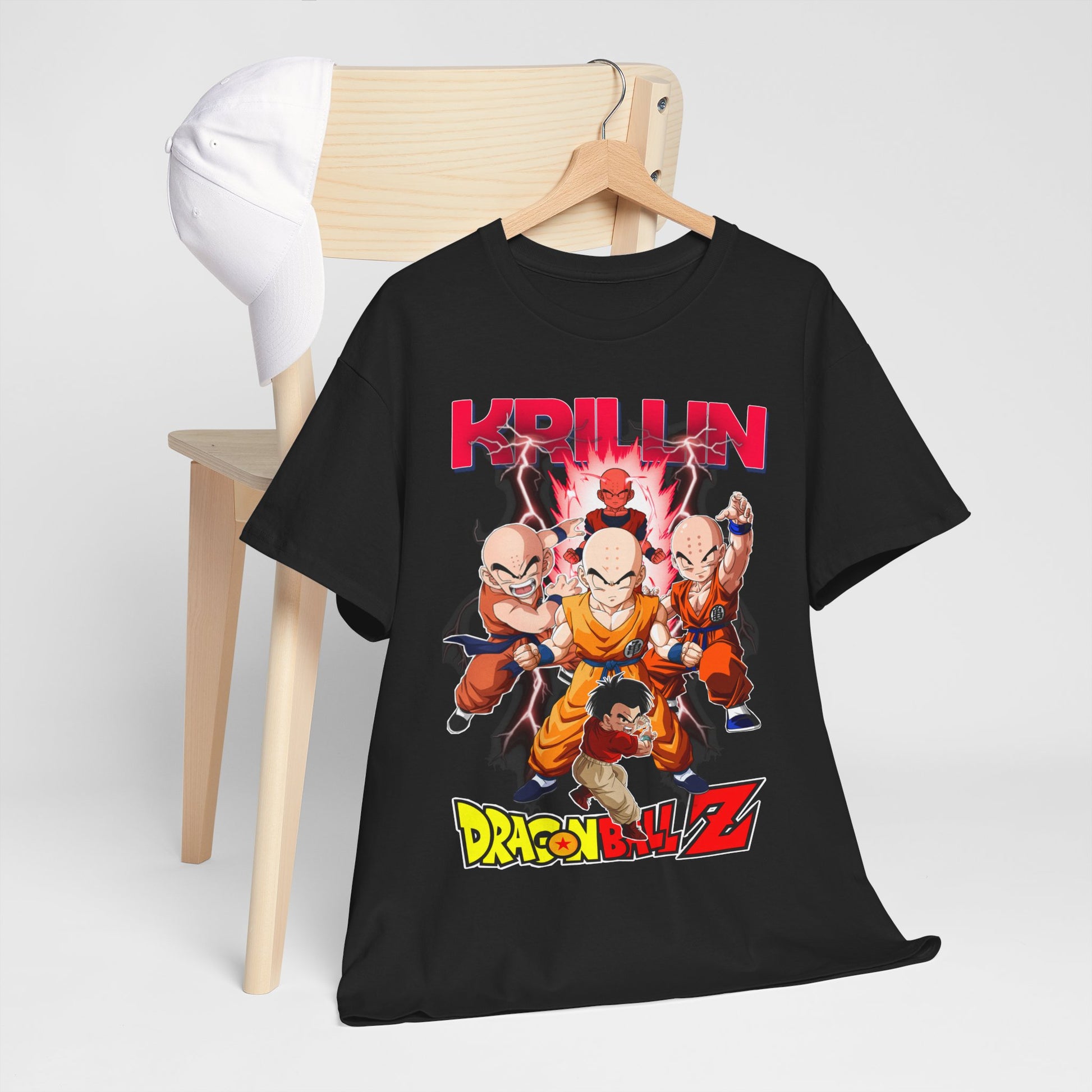 Luxurious black Dragon Ball Z T-shirt featuring Krillin and iconic characters amidst electrifying energy graphics, displayed with a fashionable cap on a minimalist wooden chair.