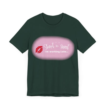 Front view of the Sabrina Carpenter Inspired Unisex Short Sleeve Tee, showcasing a vibrant lipstick print on a dark green fabric, a fusion of style and sophistication.