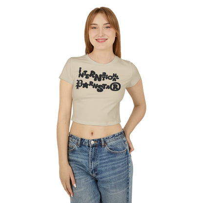Front view of a stylish cropped baby t-shirt featuring the playful phrase 'International P🌟rnstar' in vibrant lettering, modelled by a smiling woman for a contemporary look.