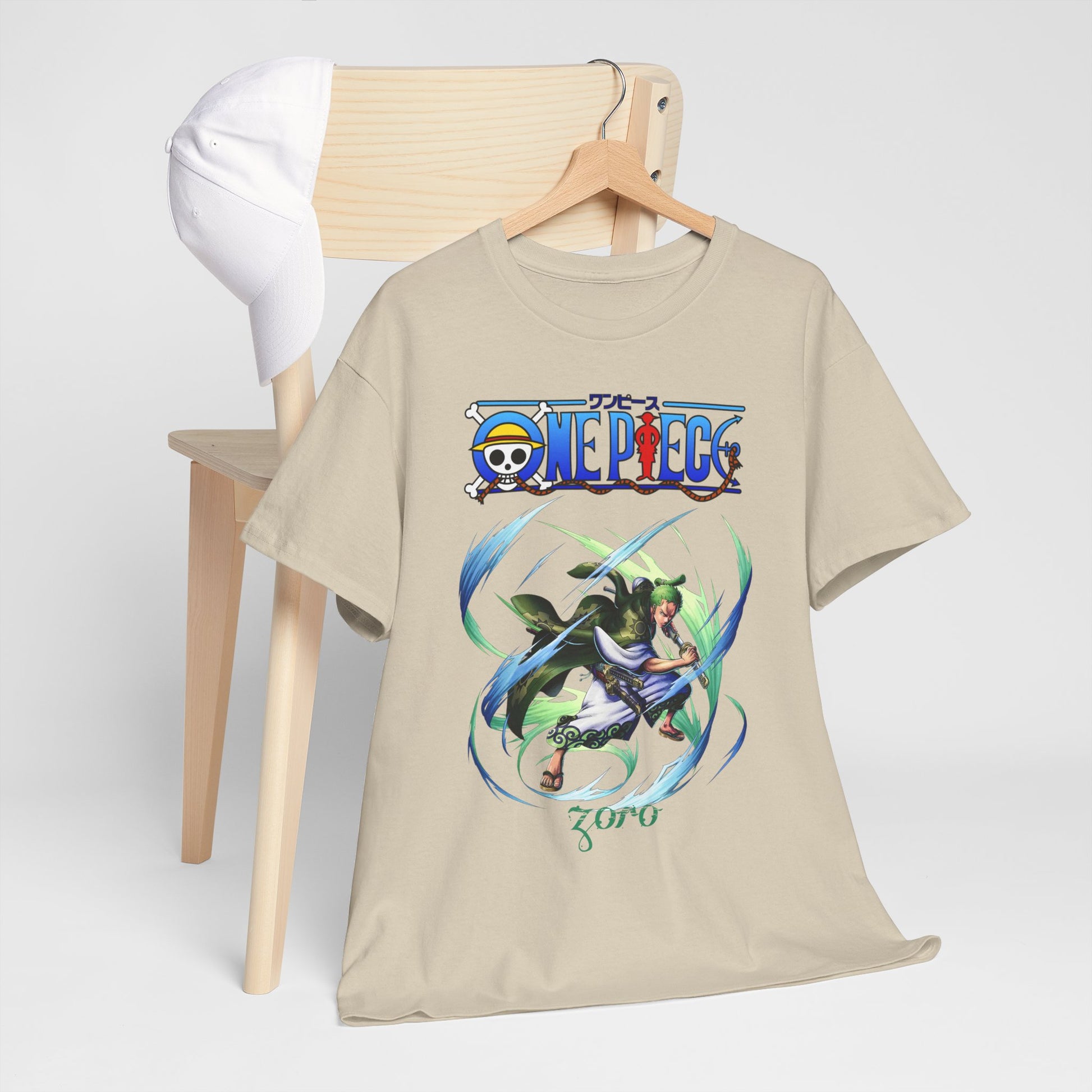 Sophisticated beige One Piece t-shirt perched on a wooden chair next to a white cap, featuring an eye-catching graphic of Zoro in action.