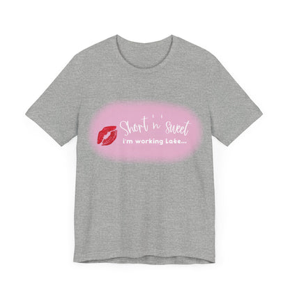 Sabrina Carpenter Inspired Unisex Short Sleeve Tee in grey, showcasing vibrant lipstick print with the phrase 'Short 'n' sweet, I'm working late...' as a fashionable statement piece.