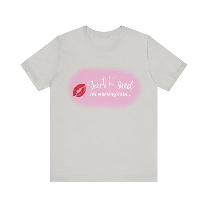 Sabrina Carpenter Inspired Unisex Short Sleeve Tee in light grey showcasing a striking lipstick print and the phrase 'Short n sweet, I'm working late...', perfect for elevating your style.