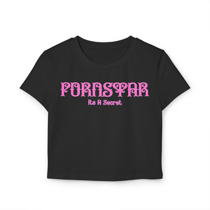 Elegant black cropped t-shirt showcasing the cheeky phrase 'Pornstar It's A Secret' in a bold pink stylized font, crafted from soft organic cotton for a luxurious feel.