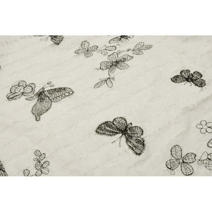 Close-up view of the delicate black butterfly pattern on the Dark In Love Zosia Lace Dress, showcasing the ethereal design set against off-white fabric.