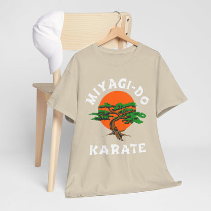 Sophisticated beige t-shirt with the Miyagi-Do Karate design draped over a wooden chair, paired with a white cap, showcasing casual elegance.