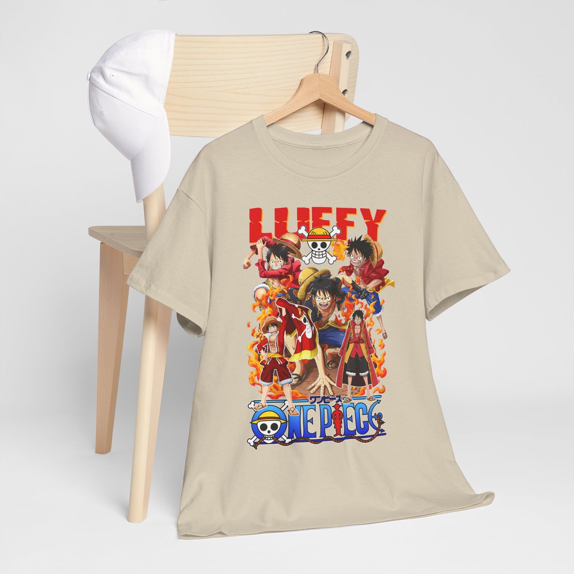 Artistic presentation of a beige t-shirt with striking One Piece anime graphics, elegantly hanging alongside a white baseball cap, perfect for a versatile and fashionable look.
