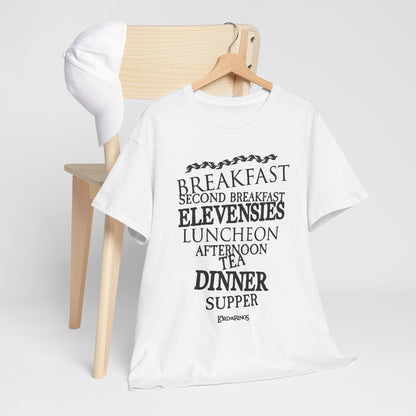 Elegant white cotton graphic t-shirt featuring whimsical meal times inspired by hobbit culture from the Lord of the Rings series, displayed on a minimalist chair with a cap.