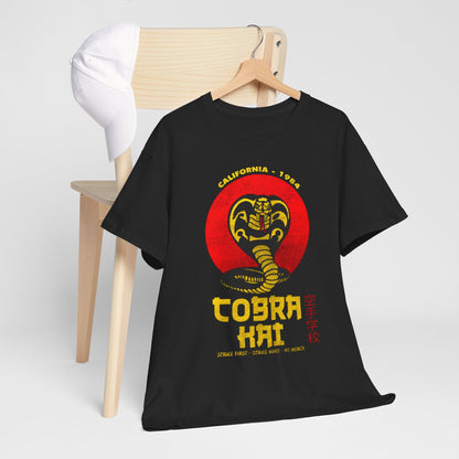 Sophisticated presentation of a black Cobra Kai graphic T-shirt draped on a wooden chair alongside a stylish cap, showcasing a vintage-inspired snake emblem. A perfect blend of comfort and elegance for martial arts lovers.