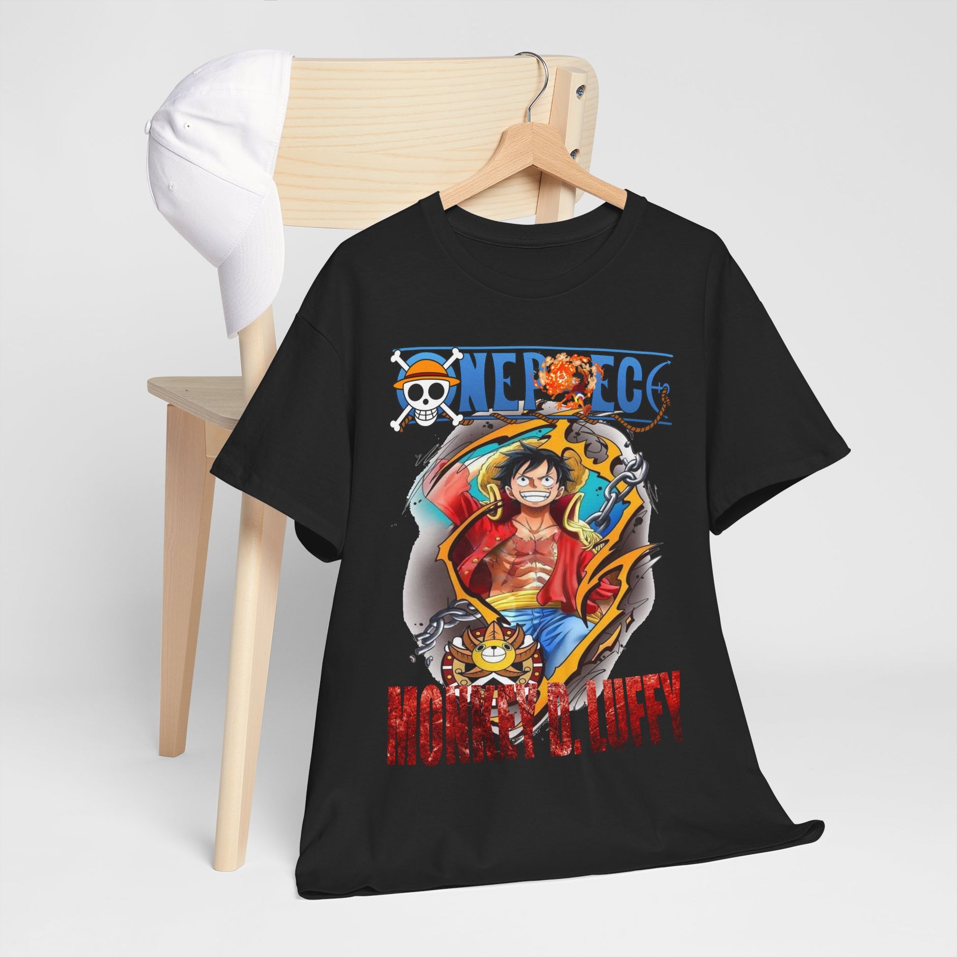 Casual presentation of the Monkey D. Luffy t-shirt on a wooden chair, accompanied by a stylish cap, highlighting its fashionable appeal.