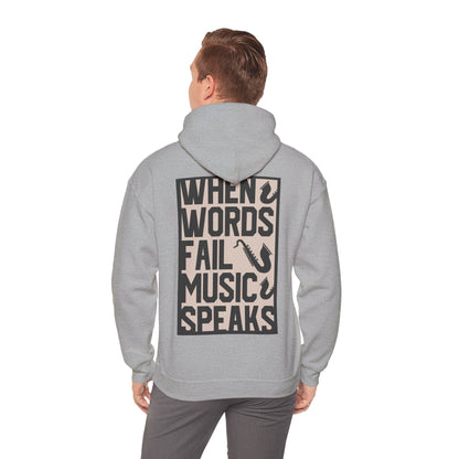 Sophisticated grey hoodie worn by a model, featuring a striking back print with the quote 'WHEN WORDS FAIL MUSIC SPEAKS' in bold typography and saxophone graphics.
