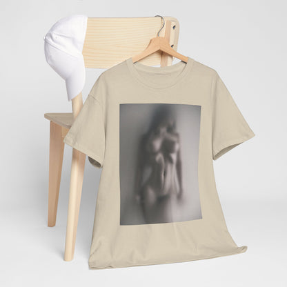 Stylish beige graphic t-shirt featuring an abstract blurred design of a figure, elegantly displayed on a wooden chair alongside a white cap.