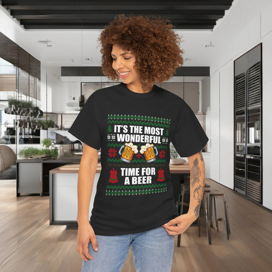 Stylish model wearing a luxurious Christmas Xmas Beer Graphic T-Shirt, featuring the text "It's the Most Wonderful Time for a Beer" surrounded by festive graphics, in a contemporary kitchen setting.
