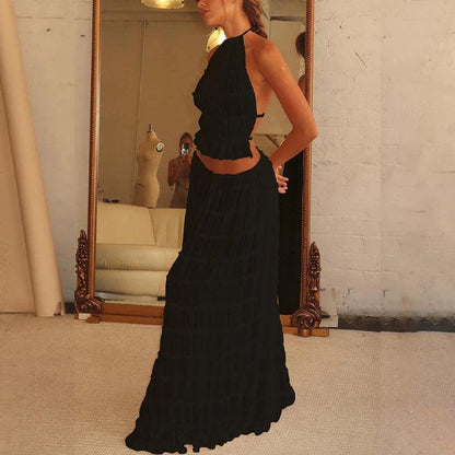 Elegant women's 2-piece sleeveless backless halter top paired with a flowing pleated long skirt in a luxurious setting, showcasing stunning summer fashion.