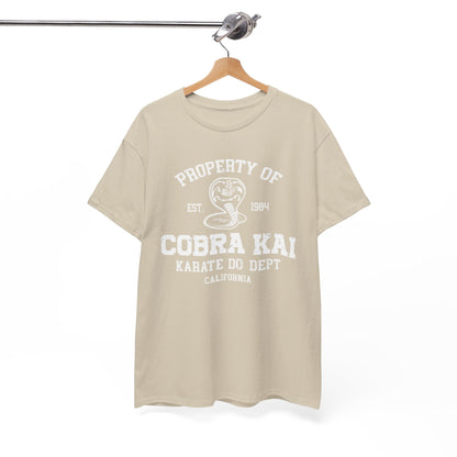 Chic display of a Cobra Kai T-shirt on a hanger, featuring the signature Cobra Kai emblem and 'Property of Cobra Kai Karate Do Dept' text in a sophisticated beige finish.