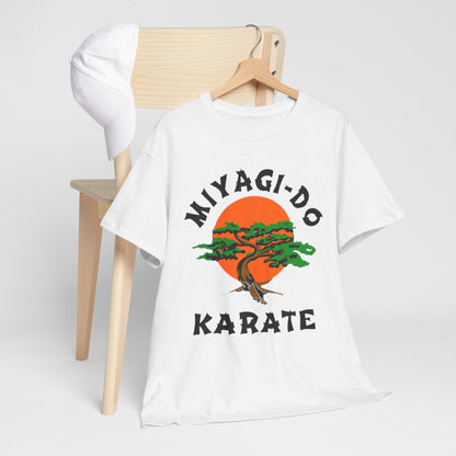 Sophisticated setting with a Miyagi-Do Karate t-shirt beside a cap, featuring a beautiful bonsai tree and sun graphic, perfect for casual yet stylish wear.
