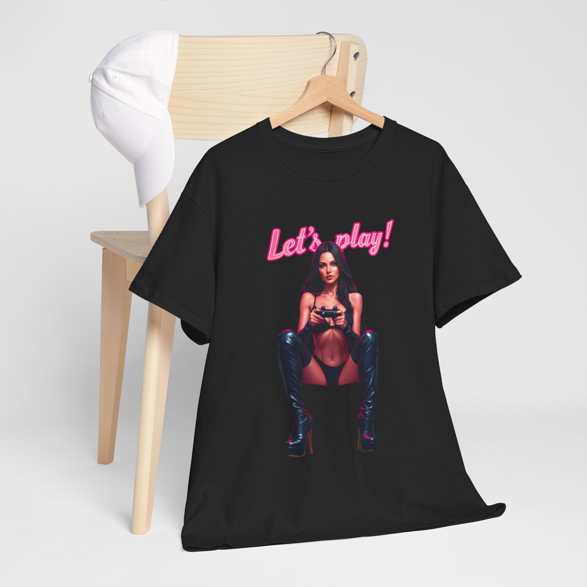 Chic black t-shirt prominently placed on a wooden chair, showcasing a striking image of a confident female gamer with a gaming controller, accompanied by vibrant pink text 'Let's play!' A sophisticated choice for gaming aficionados.