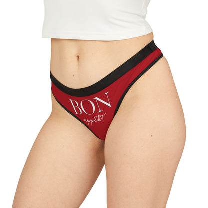 Model showcasing a seductive red thong with the phrase 'BON appétit' in stylish typography, ideal for playful gifting.