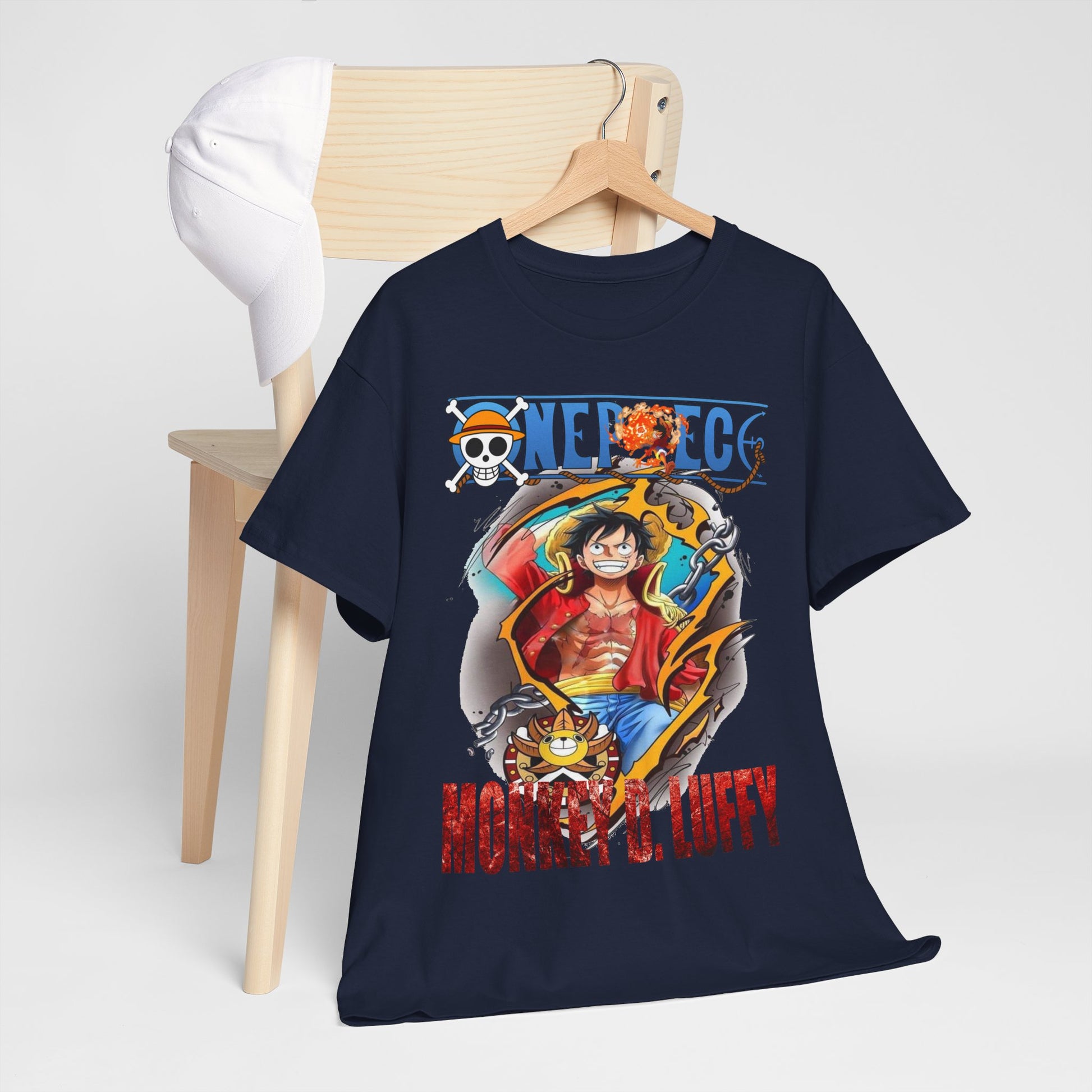Chic navy blue t-shirt with a captivating Monkey D. Luffy design, paired with a stylish baseball cap on a wooden chair.