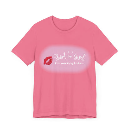 Sabrina Carpenter Inspired Unisex Short Sleeve Tee in a soft pink colour, featuring a playful lipstick print with the phrase 'Short 'n Sweet, I'm Working Late...'