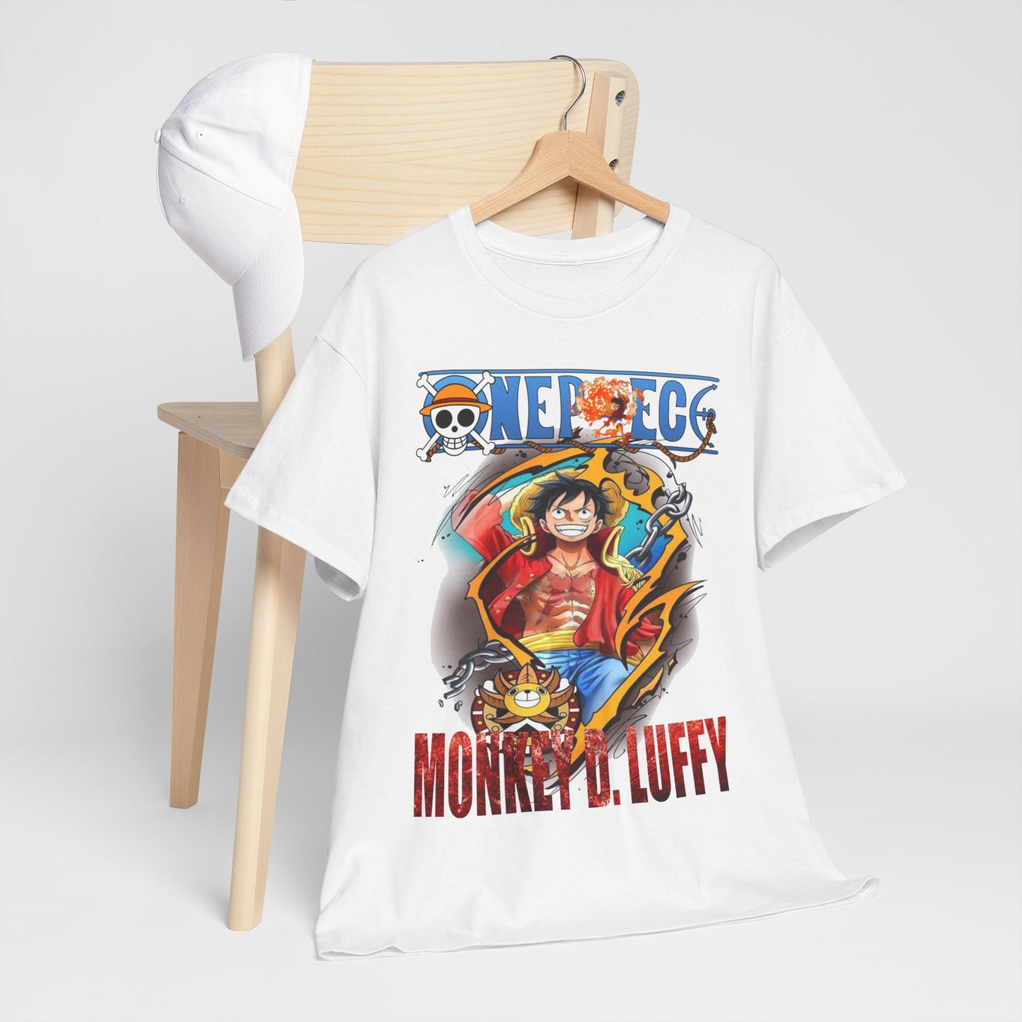 Stylish white t-shirt featuring Monkey D. Luffy graphic, artistically styled, displayed alongside a white cap on a minimalist wooden chair for a chic, adventurous look.