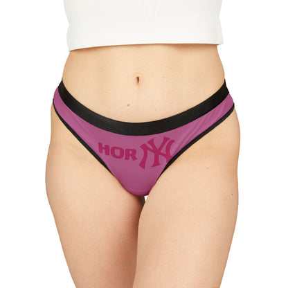 Chic women's pink thong worn by a model, accentuating curves with a trendy 'HORNY' motif and black detailing, ideal for those who embrace playful elegance in lingerie.