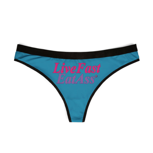 Elegant view of teal cheeky thong panties, prominently showcasing the playful phrase 'Live Fast, Eat Ass' in striking pink, perfect for adding a cheeky touch to any lingerie collection.