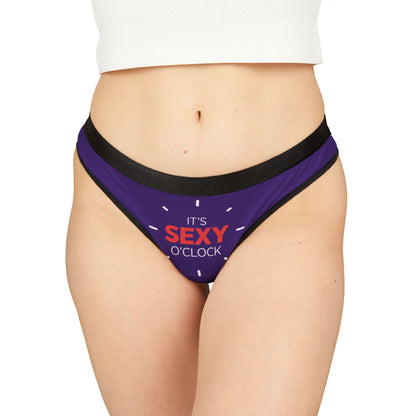 Elegant women's thong with a playful design featuring 'IT'S SEXY O'CLOCK' in bold typography, set against a rich purple background, perfect for adding a touch of whimsy to your lingerie collection.