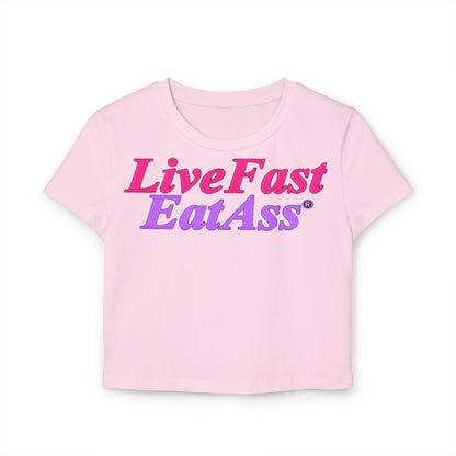 Stylish cropped t-shirt in soft pink showcasing the bold message 'Live Fast Eat Ass' in a striking gradient of pink and purple, perfect for a trendy wardrobe.