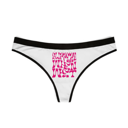 Close-up view of 'SLIPPY WHEN WET' thong panties featuring vibrant pink typography against a classic white backdrop, embodying a chic and bold lingerie style.