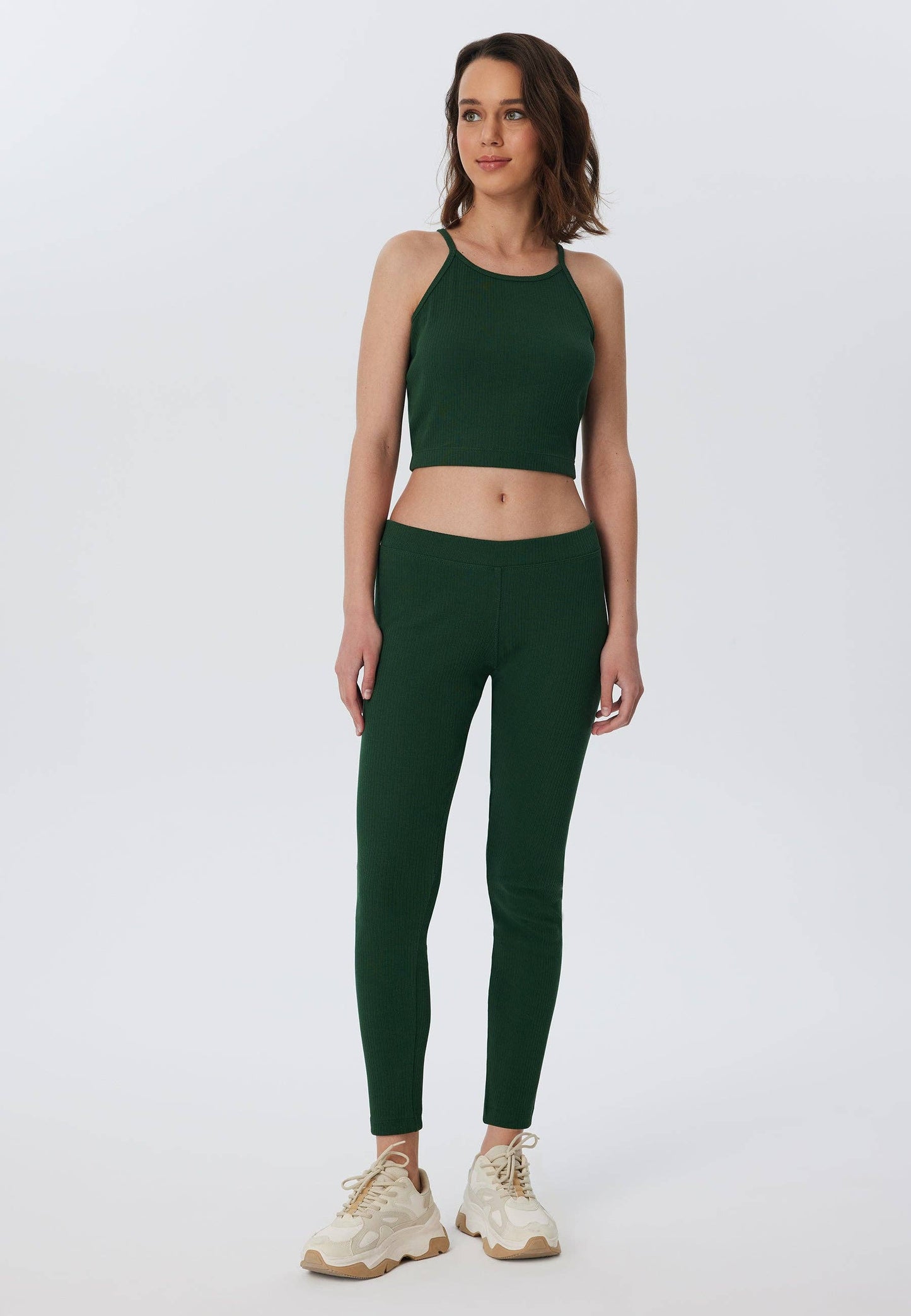 Woman wearing fashionable ribbed leggings made from 100% organic cotton, demonstrating comfort and versatility in a chic outfit.