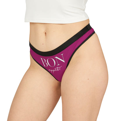 Elegantly styled women's thong with the phrase 'BON appétit' in chic typography, set against a rich purple background. This cheeky piece combines style and humour for a flirty addition to any lingerie collection.