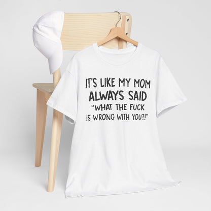 Elegant display of the Funny Mom Quote T-Shirt resting on a wooden chair with a cap, featuring the witty saying 'It's like my mom always said: What the fuck is wrong with you?!' in prominent black font, ideal for relaxed luxury.