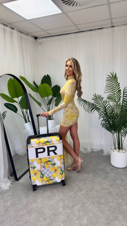 The stylish Santorini dress displayed alongside HB London Mediterranean suitcases, exemplifying the perfect summer vacation wardrobe.