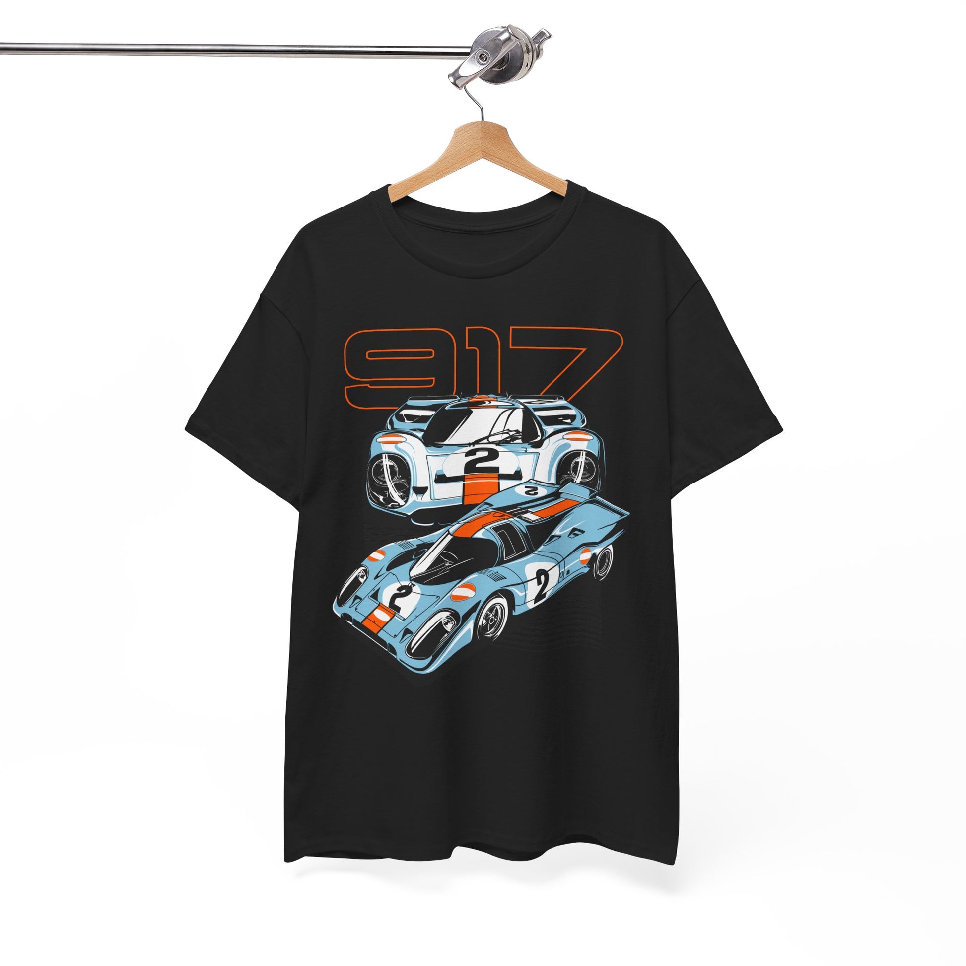 Luxurious Porsche 917 graphic t-shirt displayed on a hanger, featuring dynamic illustrations of two sleek race cars with an imposing black background and vibrant orange accents.