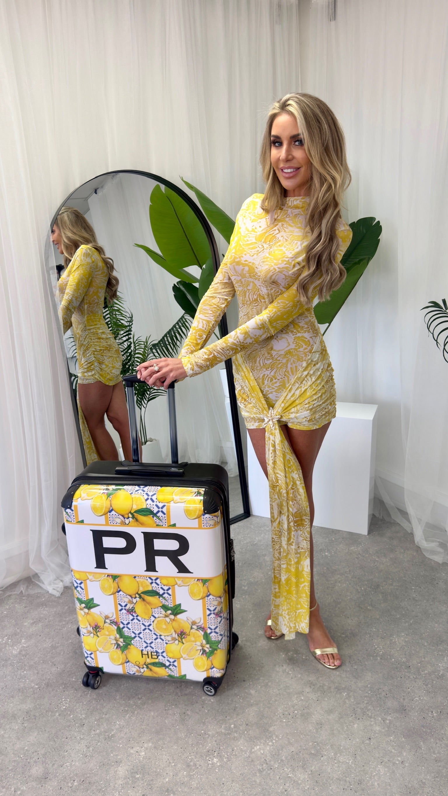 Full view of the Santorini dress styled elegantly, showcasing its sheer print and long sleeves against a sophisticated backdrop.