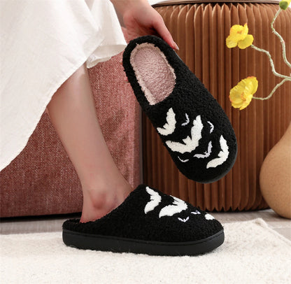 Hand holding the black version of Funny Bat Slipper Halloween Pumpkin Flat Indoor House Shoes, emphasising their unique bat pattern and sumptuous feel for Halloween gifting.