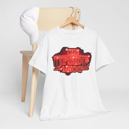 Stylish arrangement of a white T-shirt adorned with a bold 'THE UPSIDE DOWN' neon-red design, alongside a trendy cap on a wooden chair.