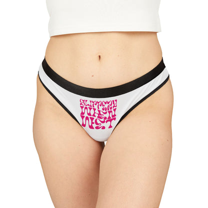 Elegant model showcasing 'SLIPPY WHEN WET' thong panties in bold pink lettering on a crisp white background, designed for a playful and luxurious feel.