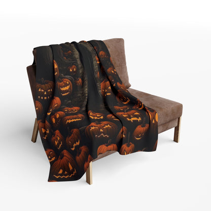 Chic Decorative and Warm Halloween Spooky Arctic Fleece Blanket draped gracefully over a plush chair, adorned with an array of festive jack-o'-lanterns.