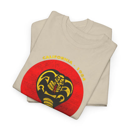 High-quality folded beige Cobra Kai T-shirts featuring the classic cobra logo and striking red circle design, symbolizing martial arts nostalgia and modern style.