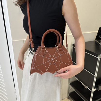 Rich brown Halloween Spider Web Saddle Bag elegantly held, showcasing skilled craftsmanship and striking spider web design, perfect for sophisticated Halloween attire.