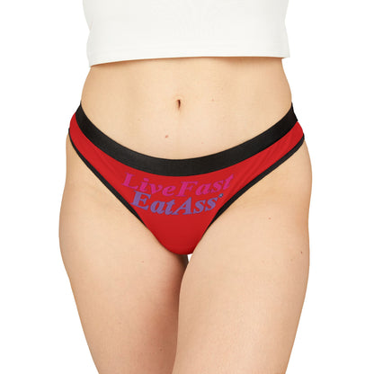 Model showcasing chic red thong panties with the phrase 'Live Fast Eat Ass' in bold typography, exemplifying a daring and confident lingerie choice.