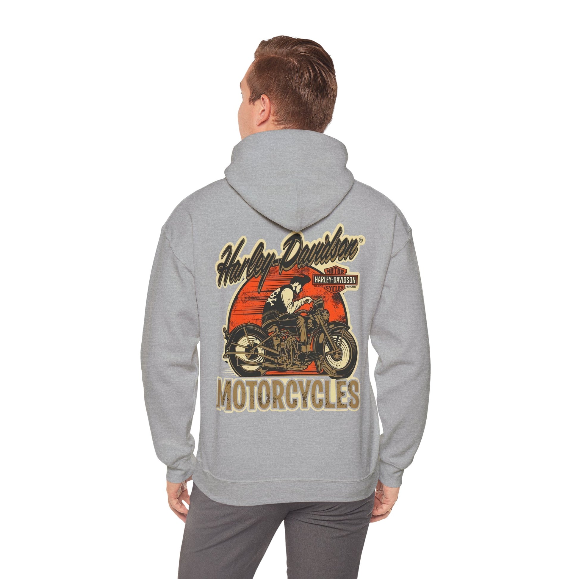 Man wearing a vintage Harley-Davidson hoodie, displaying a stunning back print of an iconic motorcycle against a vibrant sunset backdrop, exuding adventure and style.