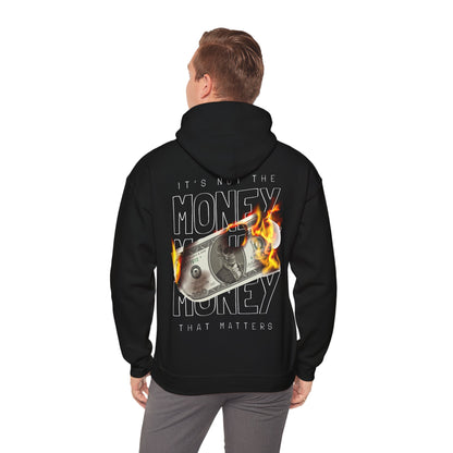 Trendy man wearing a black hoodie with an eye-catching back graphic: a flaming dollar depicting the statement 'IT'S NOT THE MONEY.' A captivating look for those who defy convention.