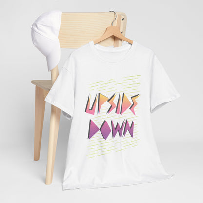 Premium unisex graphic t-shirt featuring the phrase 'UPSIDE DOWN' in vibrant pastel colours, elegantly displayed draped over a stylish wooden chair with a white cap, embodying a luxury casual aesthetic.